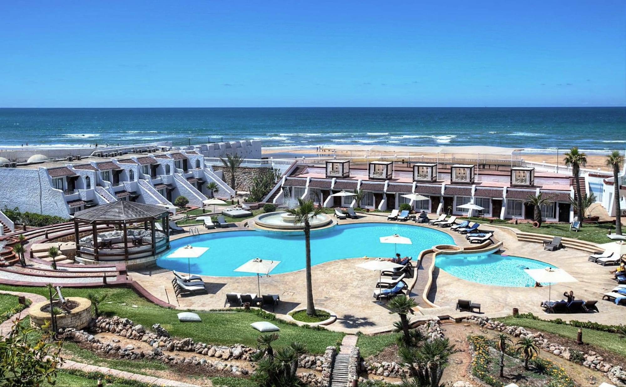 Vue aérienne du Lido : piscine, bungalows blancs en terrasses, plage et océan