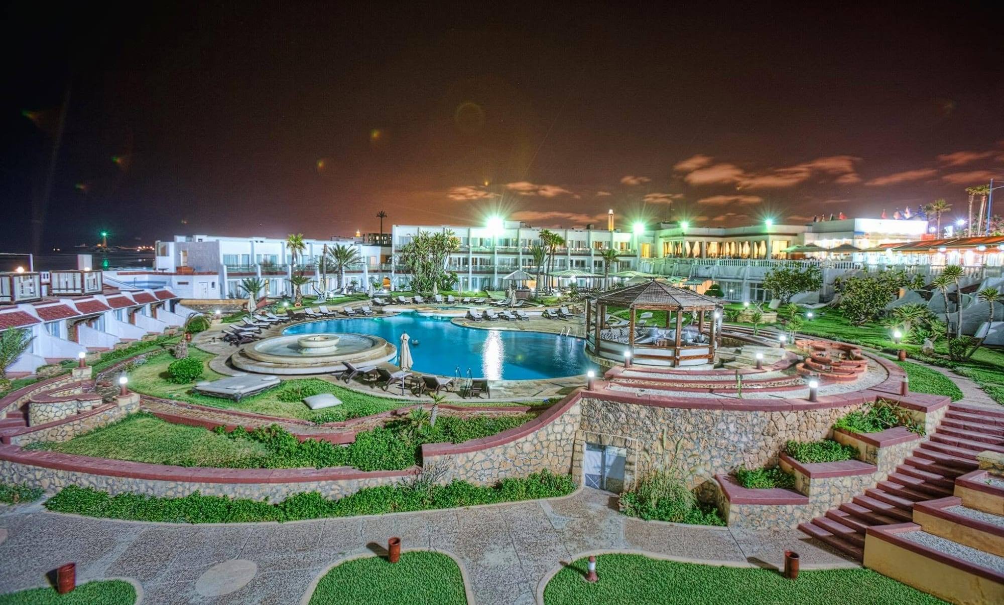 La piscine éclairée la nuit et les jardins en terrasses